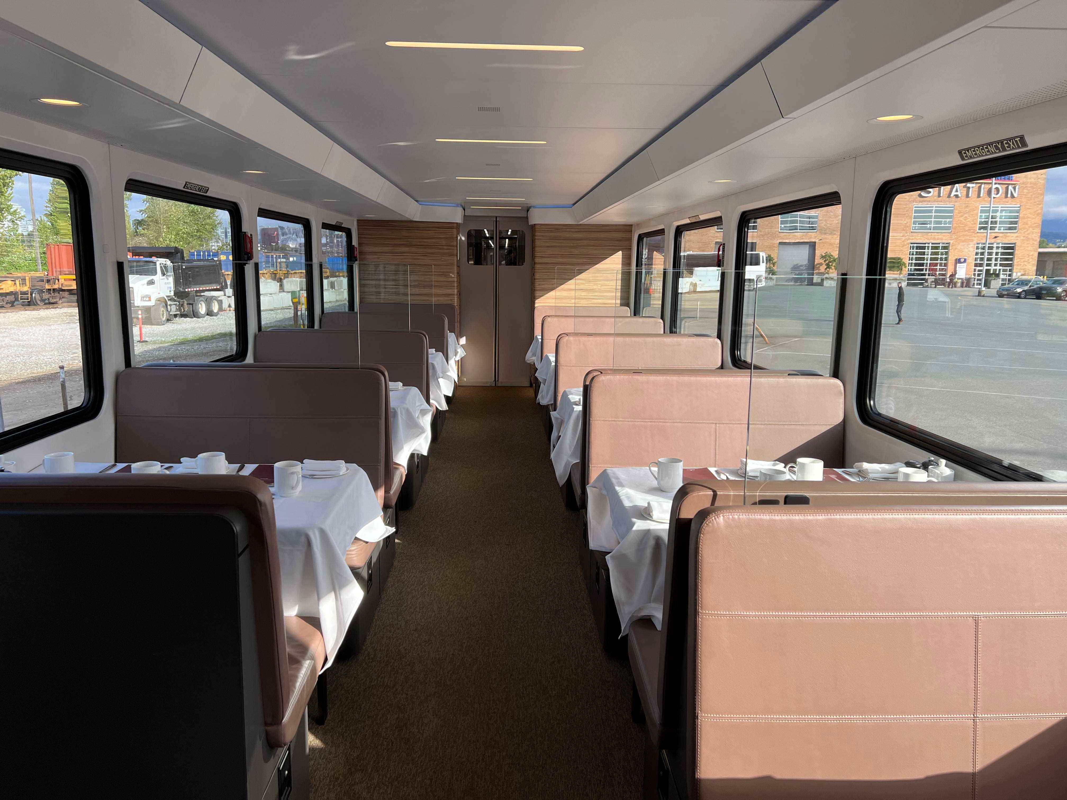 Speisewagen im Zug, mit braunen Sitzen und Tischen mit weißen Tischdecken
