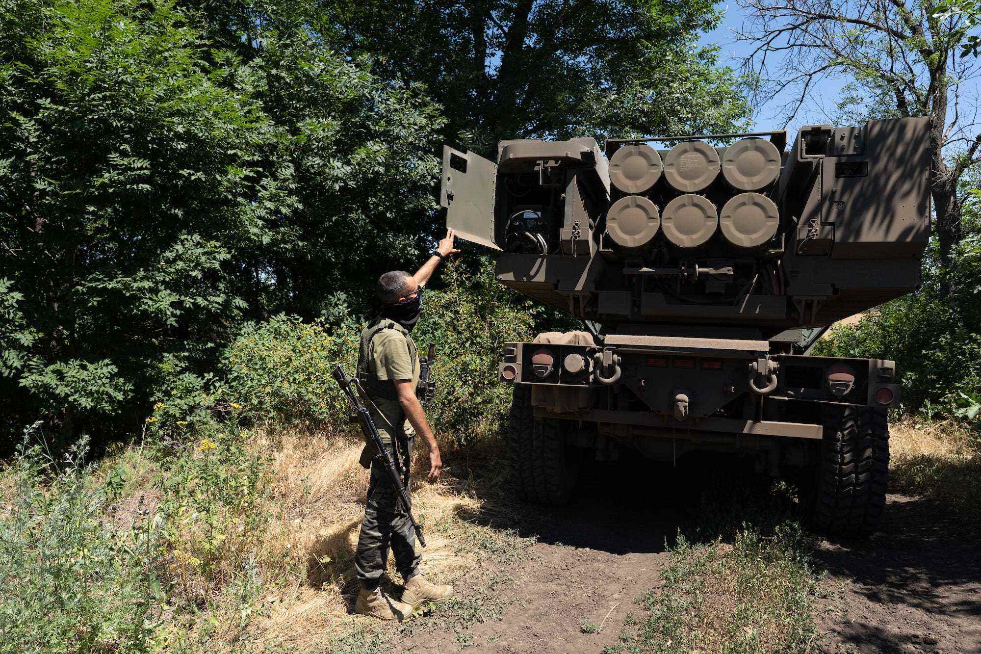 Ein ukrainischer Soldat zeigt die Raketen auf einem HIMARS-Fahrzeug zwischen einigen Bäumen