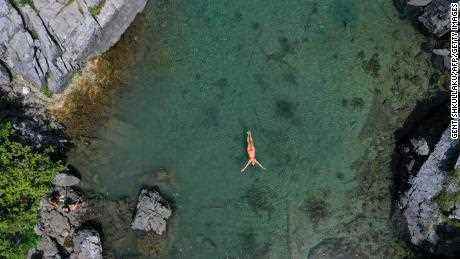 Eine Frau schwimmt am 4. August 2021 im Xhemas-See, einem kleinen natürlichen See im Valbona-Nationalpark in der Nähe von Dragobi, um sich abzukühlen.