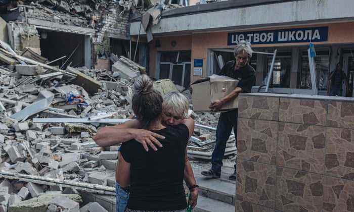 Zwei Lehrer umarmen sich, als sie sehen, wie ihre Schule am 24. Juli in Bakhmut, Ukraine, von der russischen Armee beschossen wird.