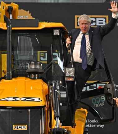 Der britische Premierminister Boris Johnson winkt dieses Jahr bei seinem Besuch in der JCB-Fabrik in Vadodara von einem Bagger.