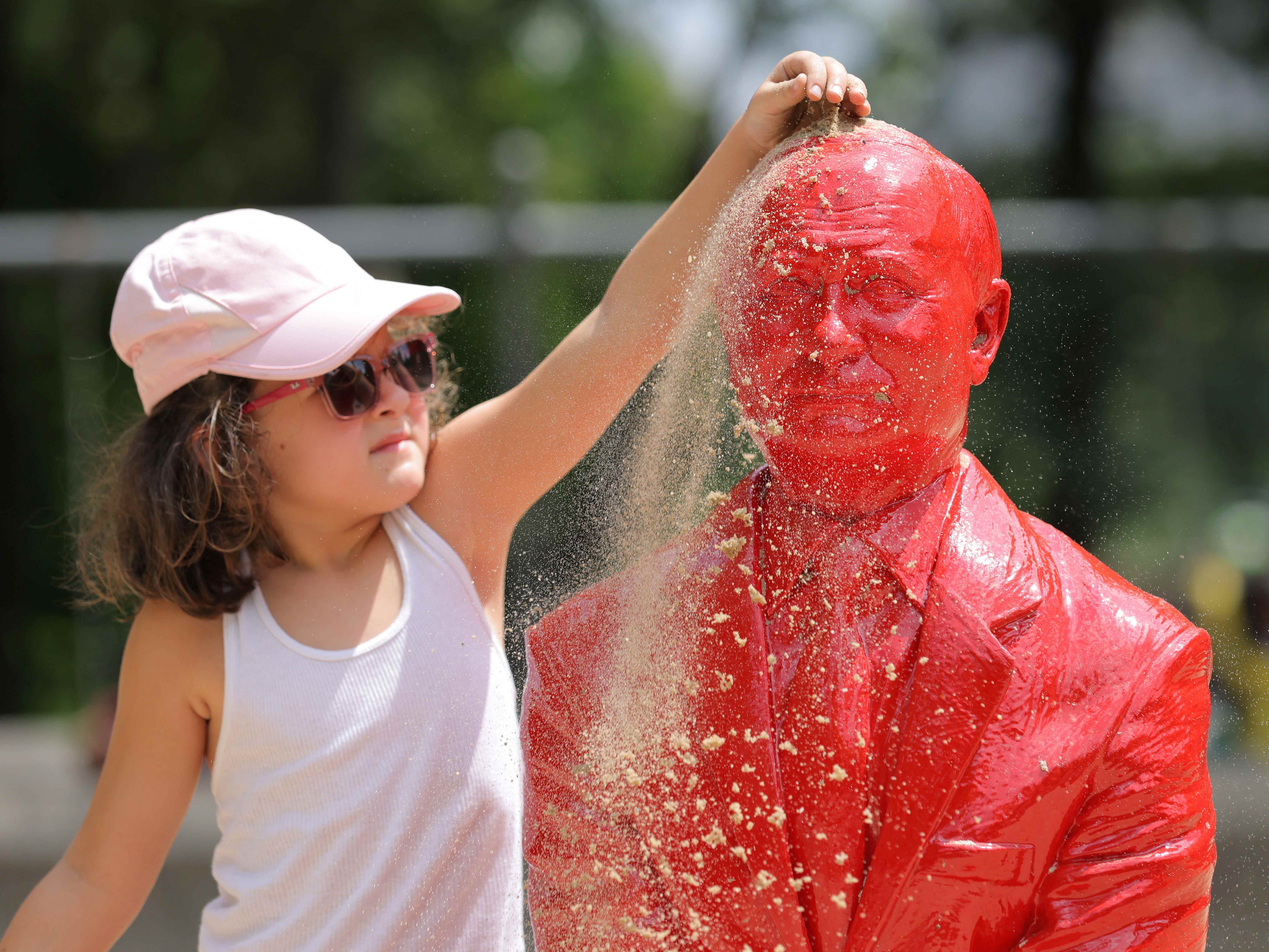 Ein Kind schüttet Sand auf eine Statue des russischen Präsidenten Wladimir Putin, der auf einem Panzer fährt, der vom französischen Künstler James Colomina im Central Park in Manhattan, New York City, USA, am 2. August 2022 geschaffen wurde.