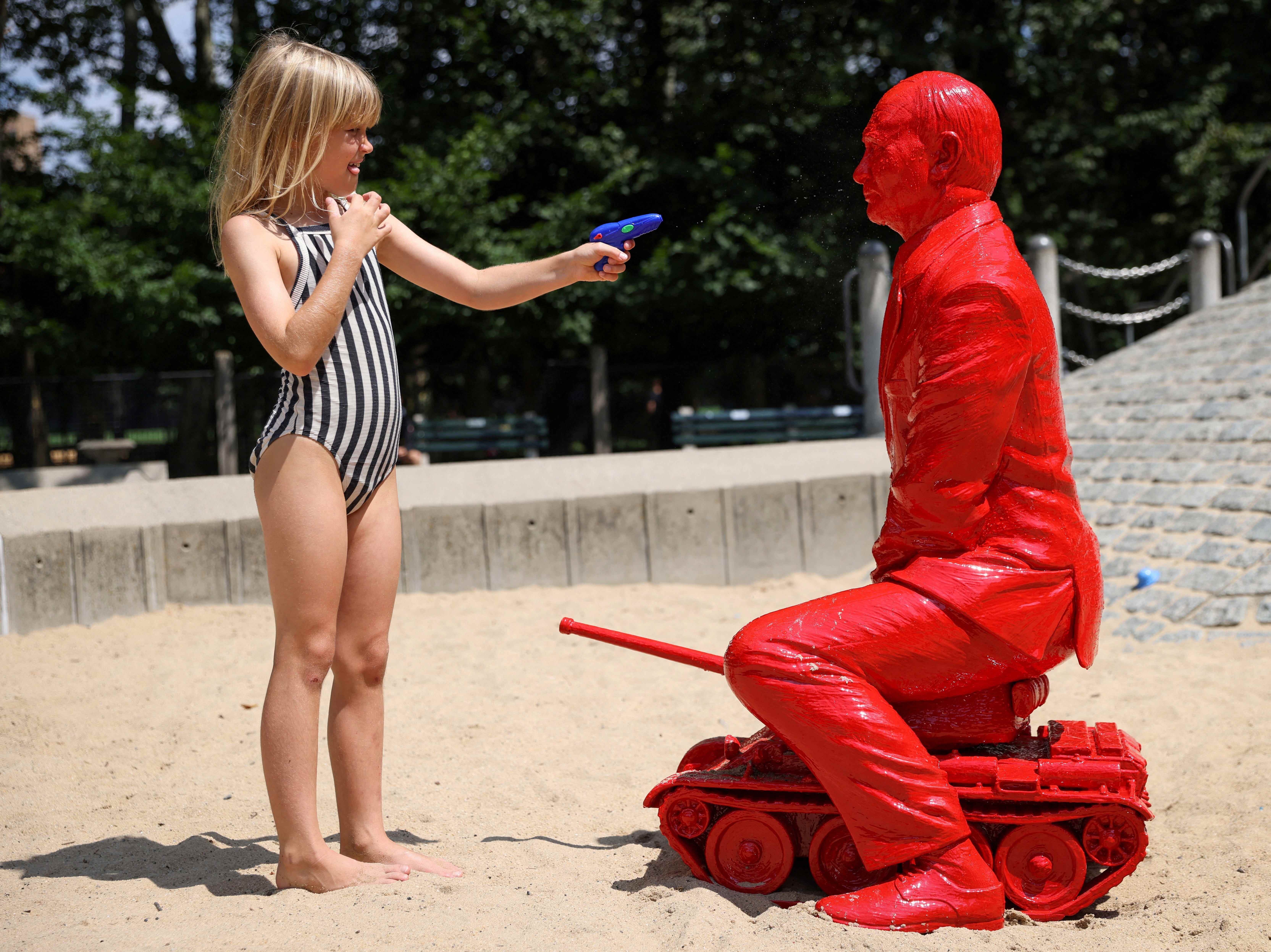 Ein Kind richtet eine Wasserpistole auf eine Statue des russischen Präsidenten Wladimir Putin, der auf einem Panzer des französischen Künstlers James Colomina reitet, auf einem Spielplatz im Central Park in Manhattan, New York City, USA, 2. August 2022.