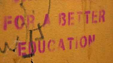 Ein Bild einer hellbraunen Wand mit einer rosafarbenen Schablone mit der Aufschrift „Für eine bessere Bildung“