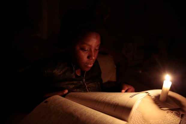 Ruvimbo Makombe liest bei Kerzenlicht während des Stromausfalls in Harare, 28. Juli 2022.