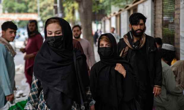 Frauen bedecken ihre Gesichter, während sie eine Straße in Kabul entlang gehen
