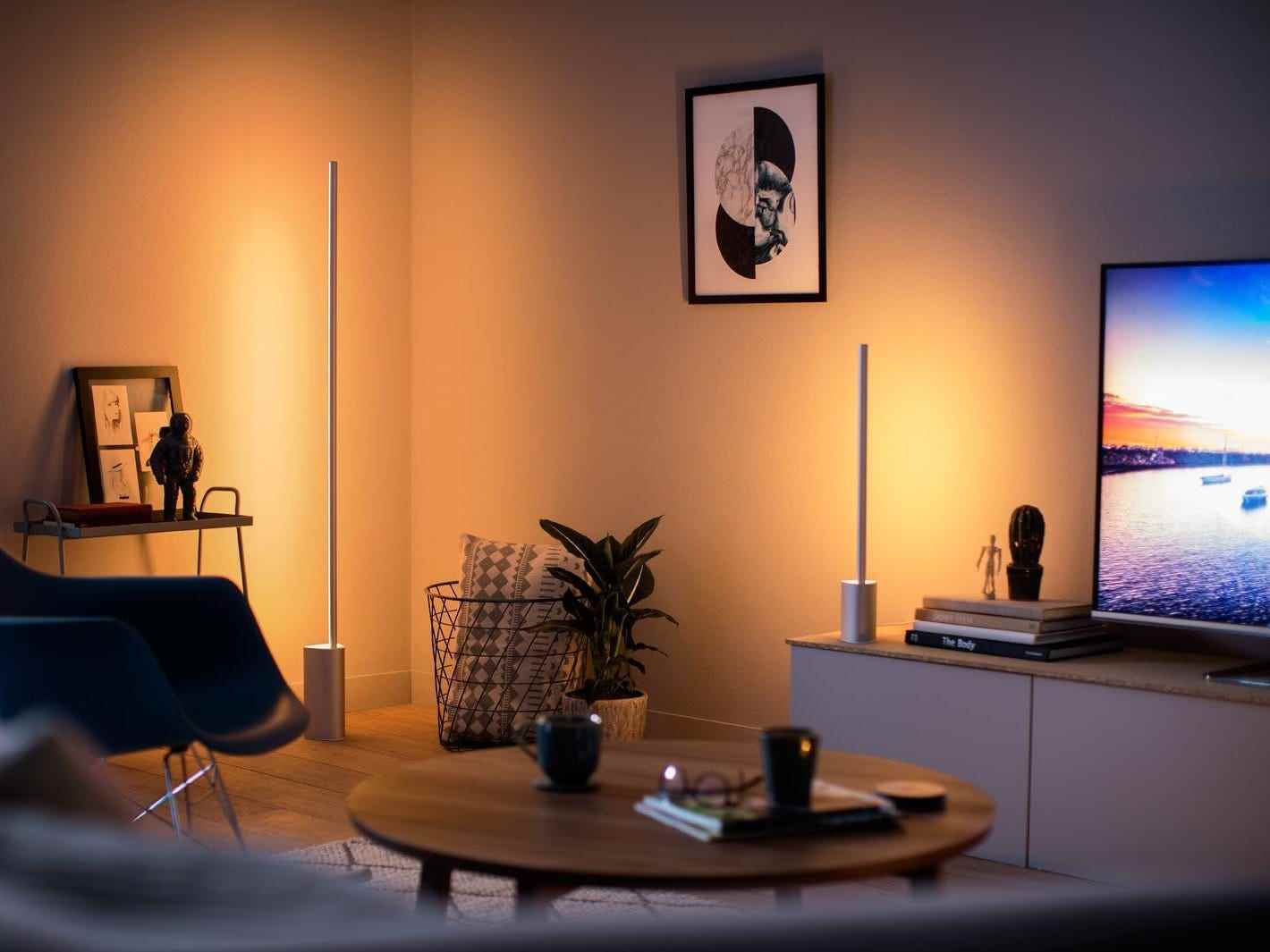 Ein abgedunkeltes Wohnzimmer mit einer großen, schlanken Stehlampe und einer Dia-Tischlampe