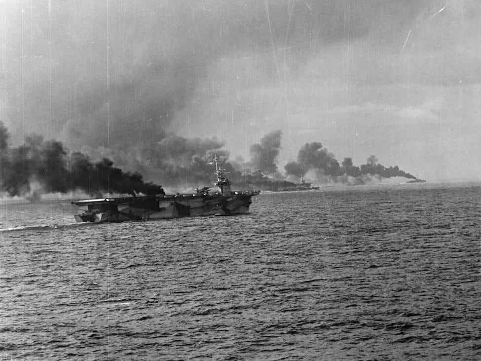 Schlacht im Golf von Leyte, Schlacht vor Samar, 25. Oktober 1944. Die USS Gambier Bay (CVE 73) und ein weiterer Eskortenträger sowie zwei Eskortenzerstörer machen Rauch.