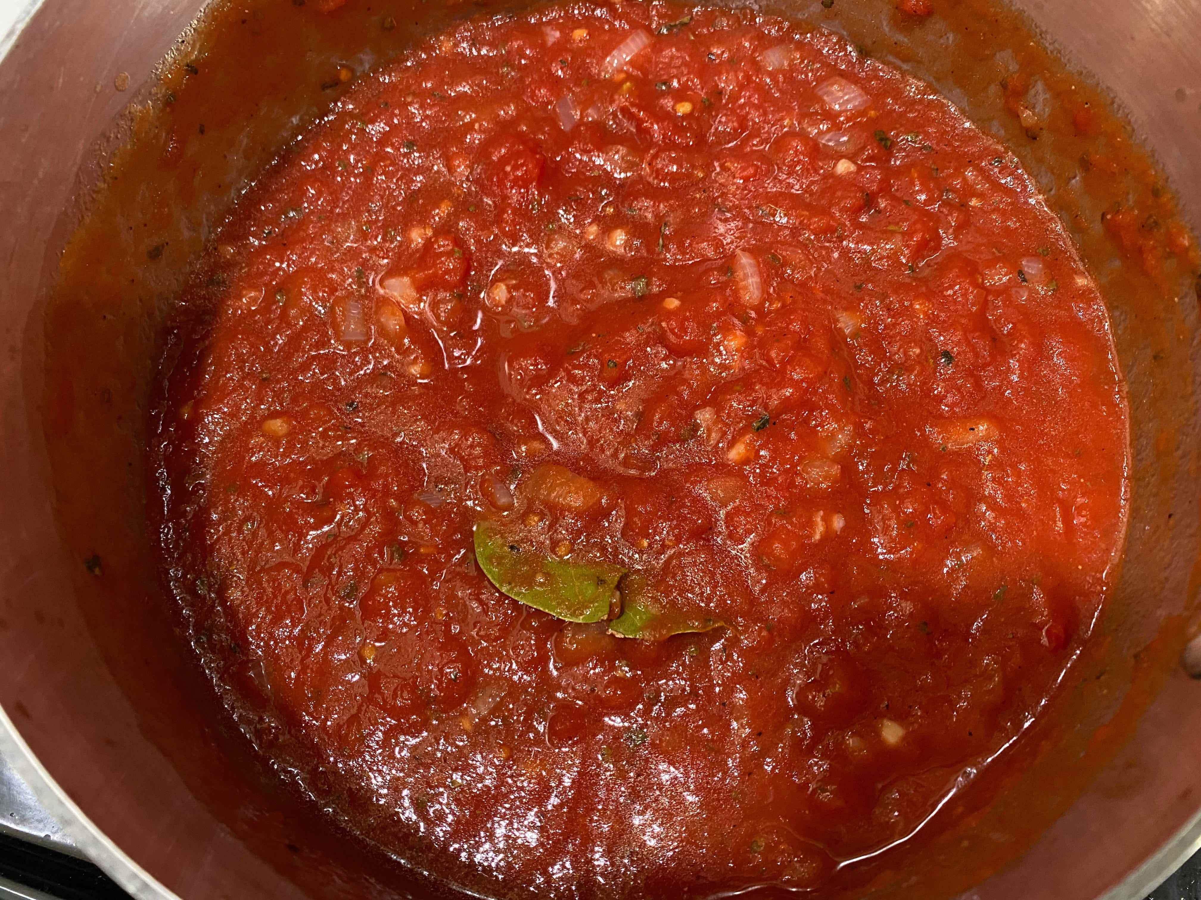 Marinara-Sauce, die im Topf mit einem Lorbeerblatt sprudelt