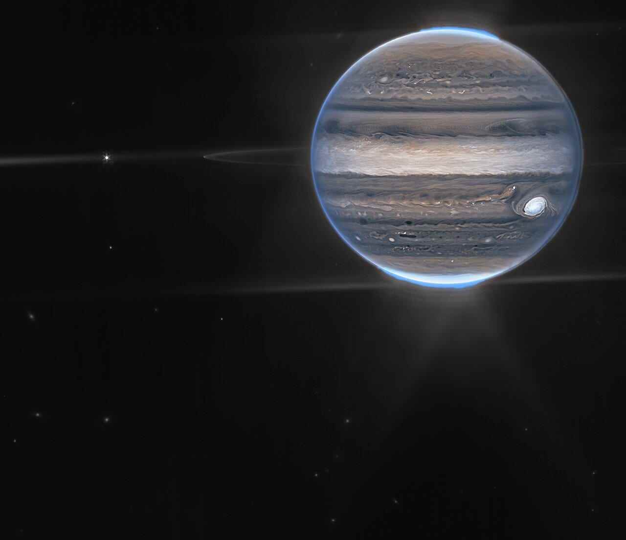 Weitfeldansicht von Jupiter, aufgenommen von Webb.  Die unscharfen Flecken im unteren Hintergrund sind wahrscheinlich Galaxien.