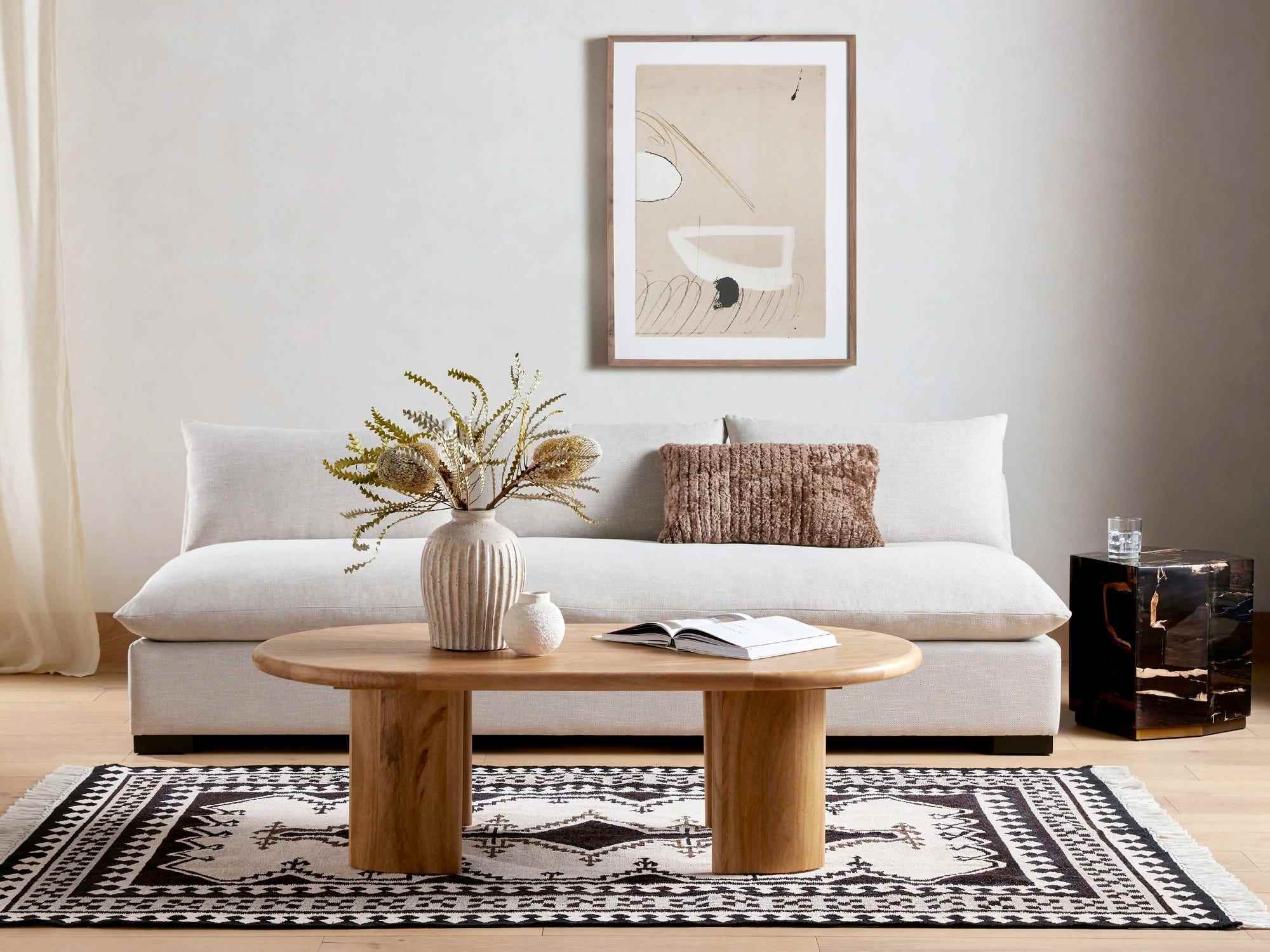 Ein haferflockenfarbenes Grant Sofa von Four Hands steht hinter einem hölzernen Couchtisch in einem Wohnzimmer.