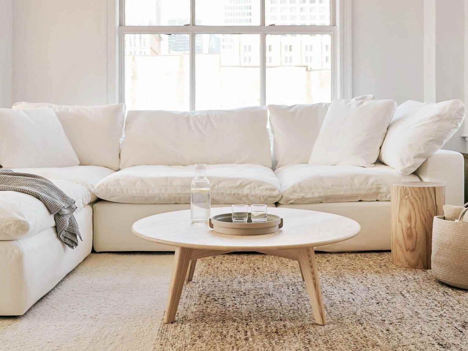 Ein weißes Sundays Movie Night Sofa steht in einem Wohnzimmer hinter einem Couchtisch aus Holz.
