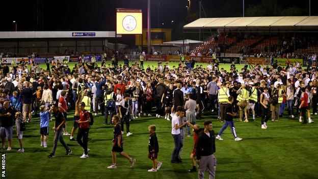 Fans von Crawley Town feiern am Ende des Spiels der zweiten Runde des Carabao Cup auf dem Spielfeld