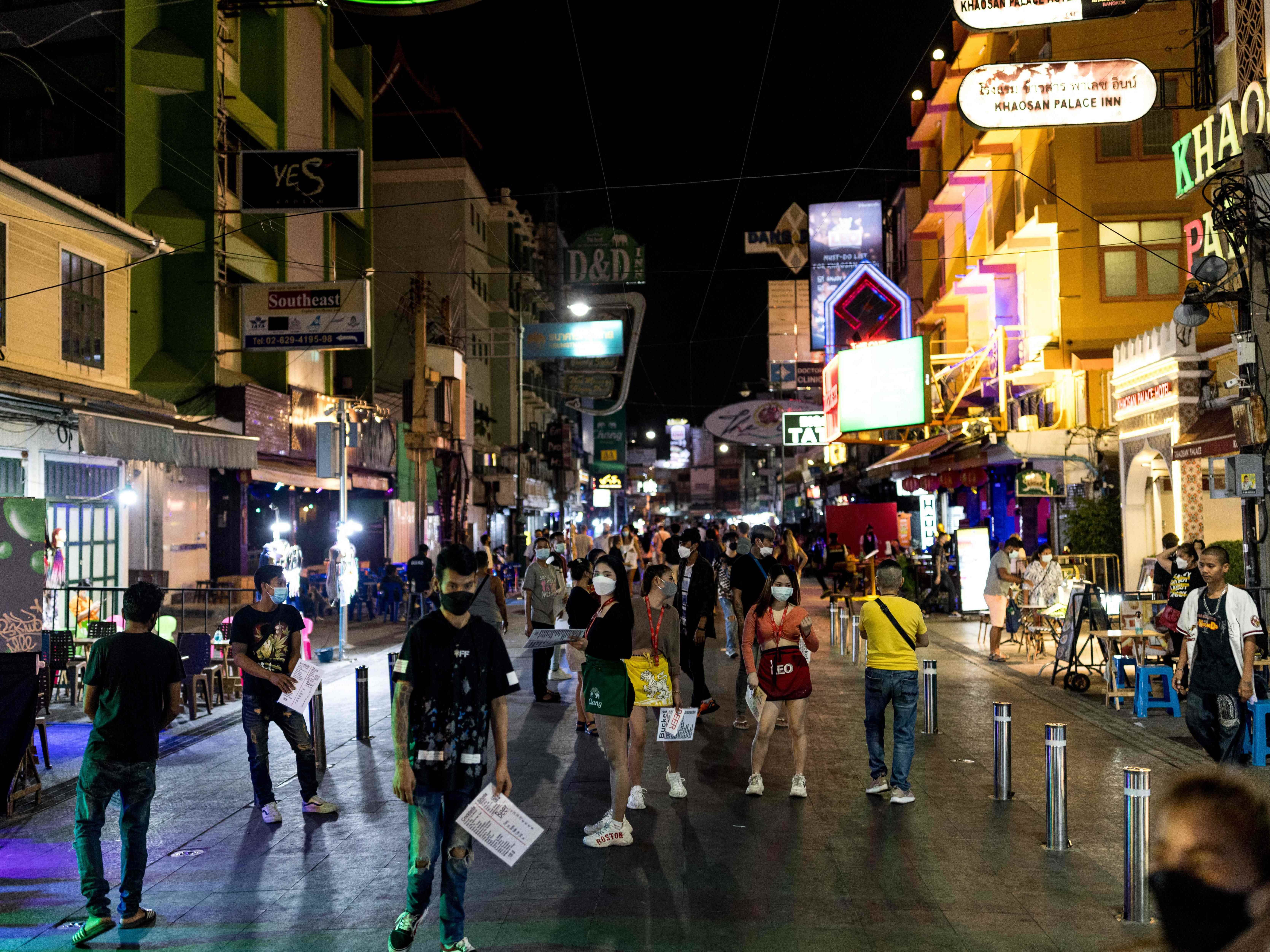 Bar- und Restaurantangestellte warten am 10. Dezember 2021 entlang der beliebten Touristen- und Ausgehmeile Khao San Road in Bangkok auf Kunden.