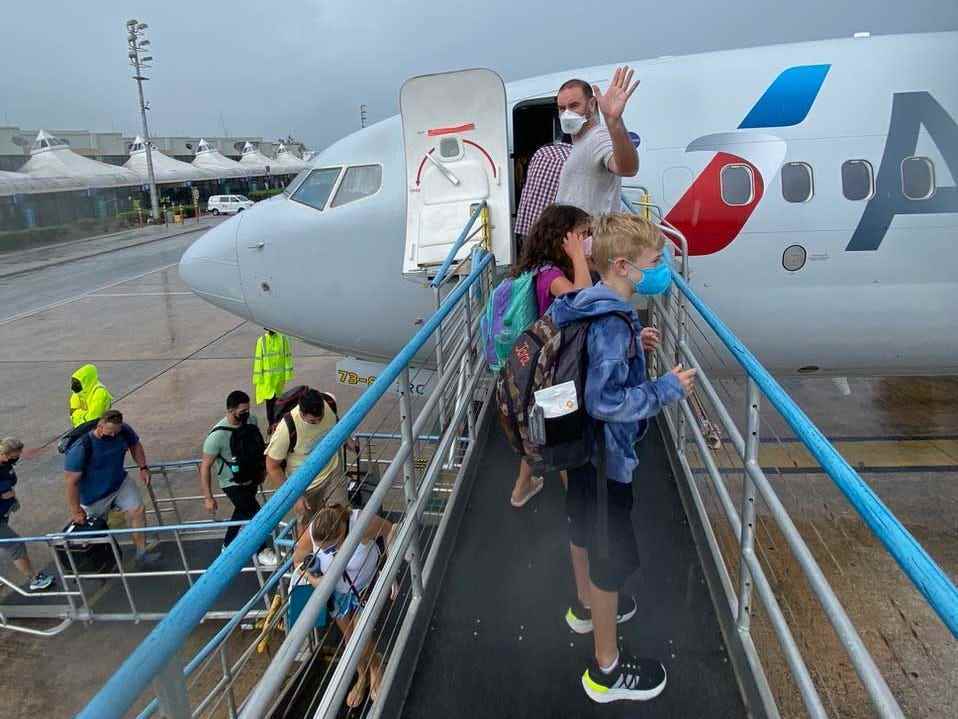 Ein Mann winkt, als er mit seinen beiden Kindern in ein Flugzeug der American Airlines steigt.
