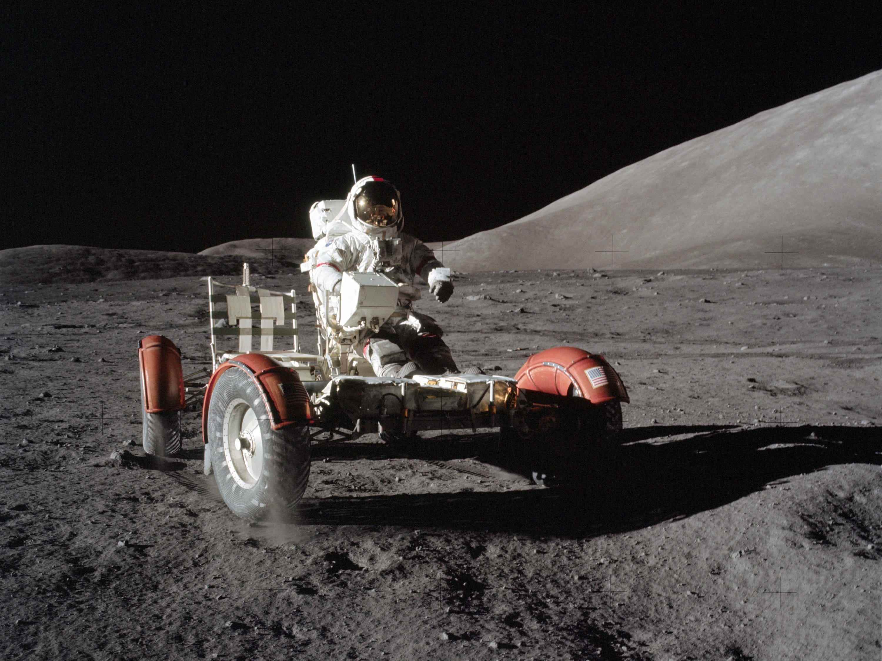 astronaut im raumanzug sitzt auf einer lunar-rover-fahrzeugplattform mit rädern auf dem mond