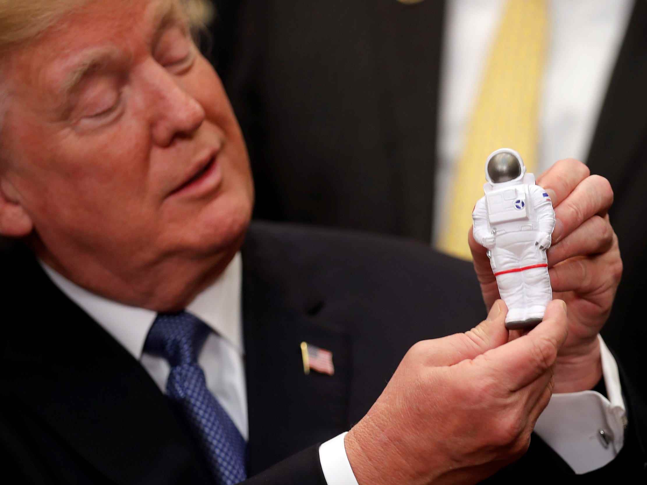 Donald Trump hält eine kleine Astronautenfigur hoch
