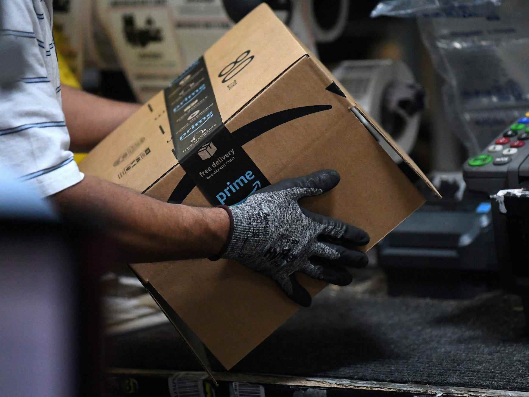 Ein Arbeiter stellt einen Karton für die Lieferung in einem Amazon-Versandzentrum zusammen
