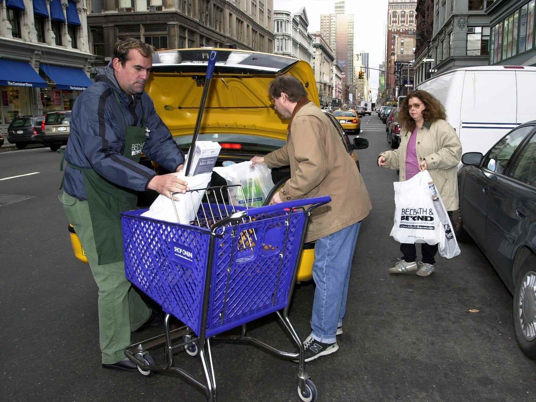 Ein Mitarbeiter von Bed Bath & Beyond hilft Kunden, ihre Einkäufe in den Kofferraum eines Taxis zu laden
