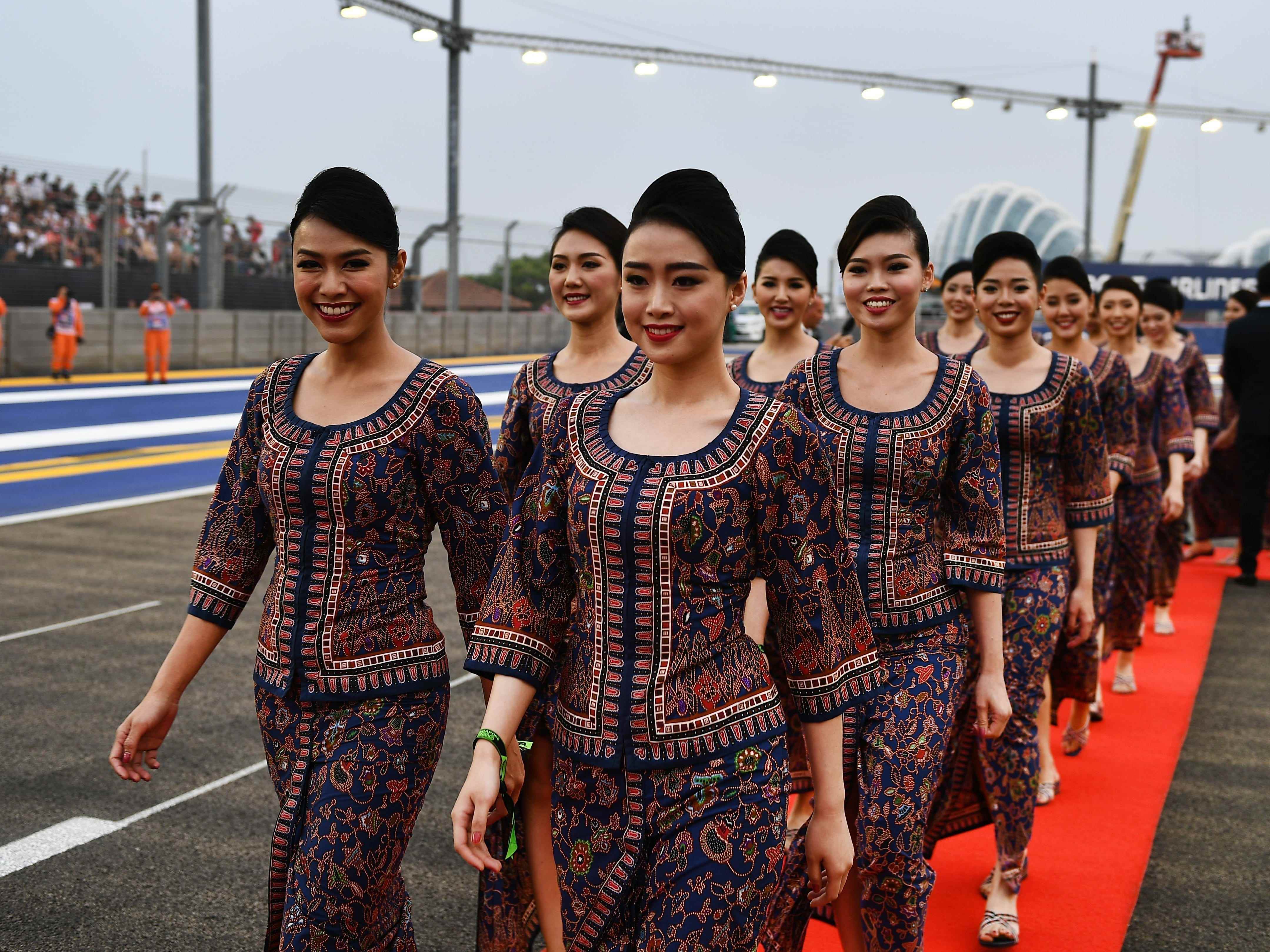 Ein Team von Flugbegleitern von Singapore Airlines läuft über einen roten Teppich.