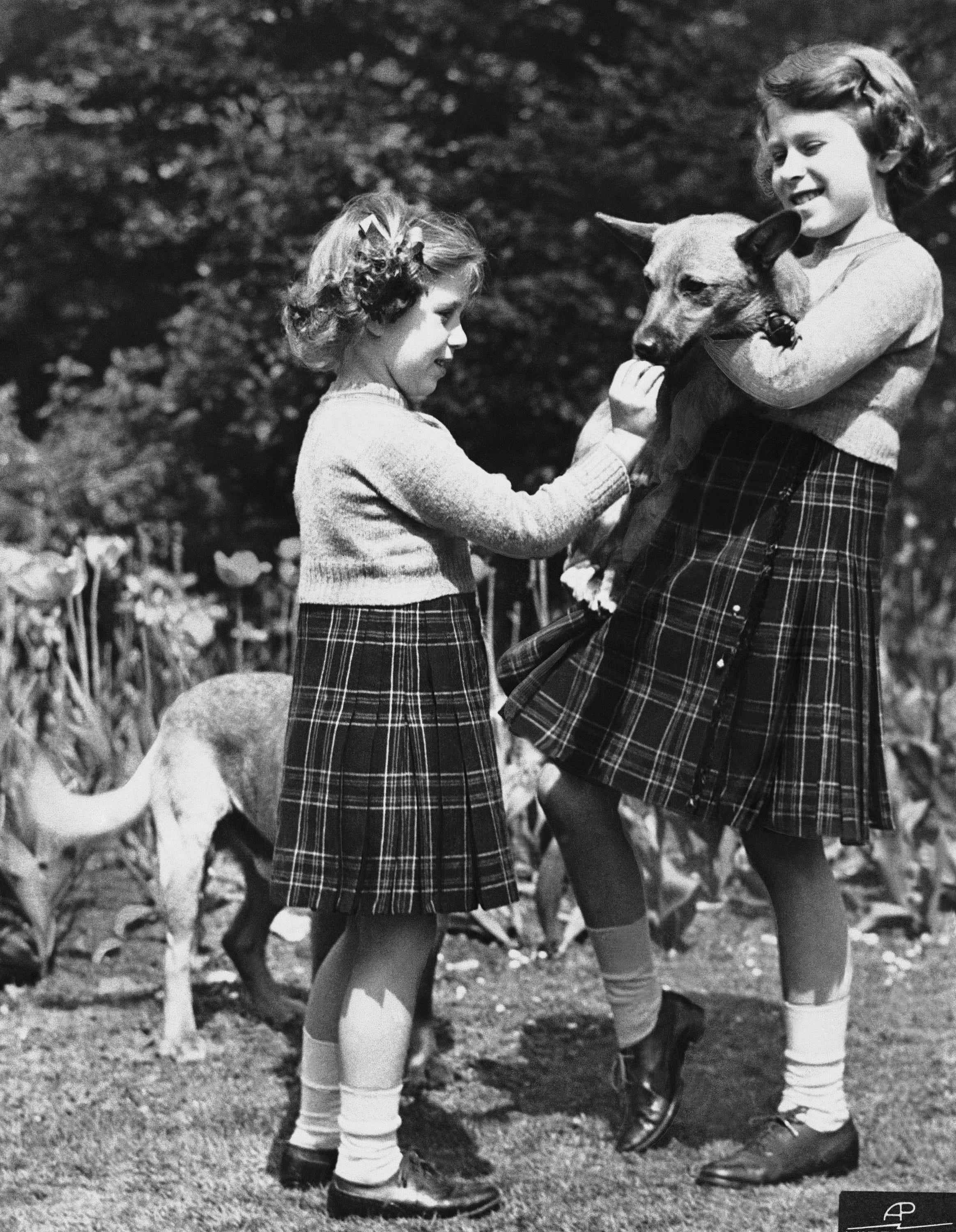 Queen Elizabeth (rechts) und Prinzessin Margaret spielen 1936 mit Corgis.