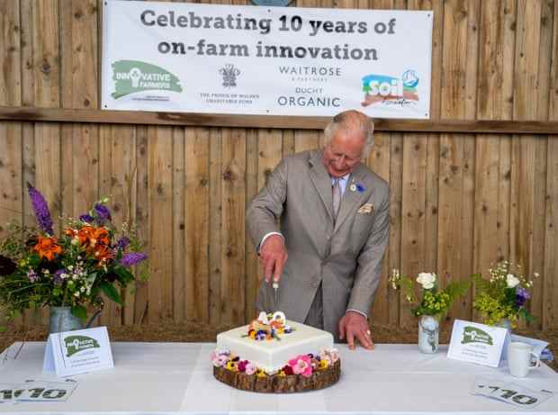 Der damalige Prinz Charles schneidet im Juli in einem Duchy Organic Pop-up-Café in Launceston mit Mitgliedern des Innovative Farmer-Netzwerks einen festlichen Kuchen an.