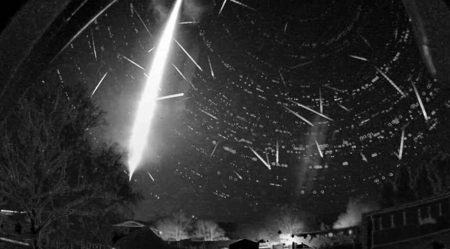 Schwarz-Weiß-Bild des Nachthimmels mit Streifen von Meteoriten, mit einem ungewöhnlich großen und hellen Blitz, der fast von oben nach unten verläuft