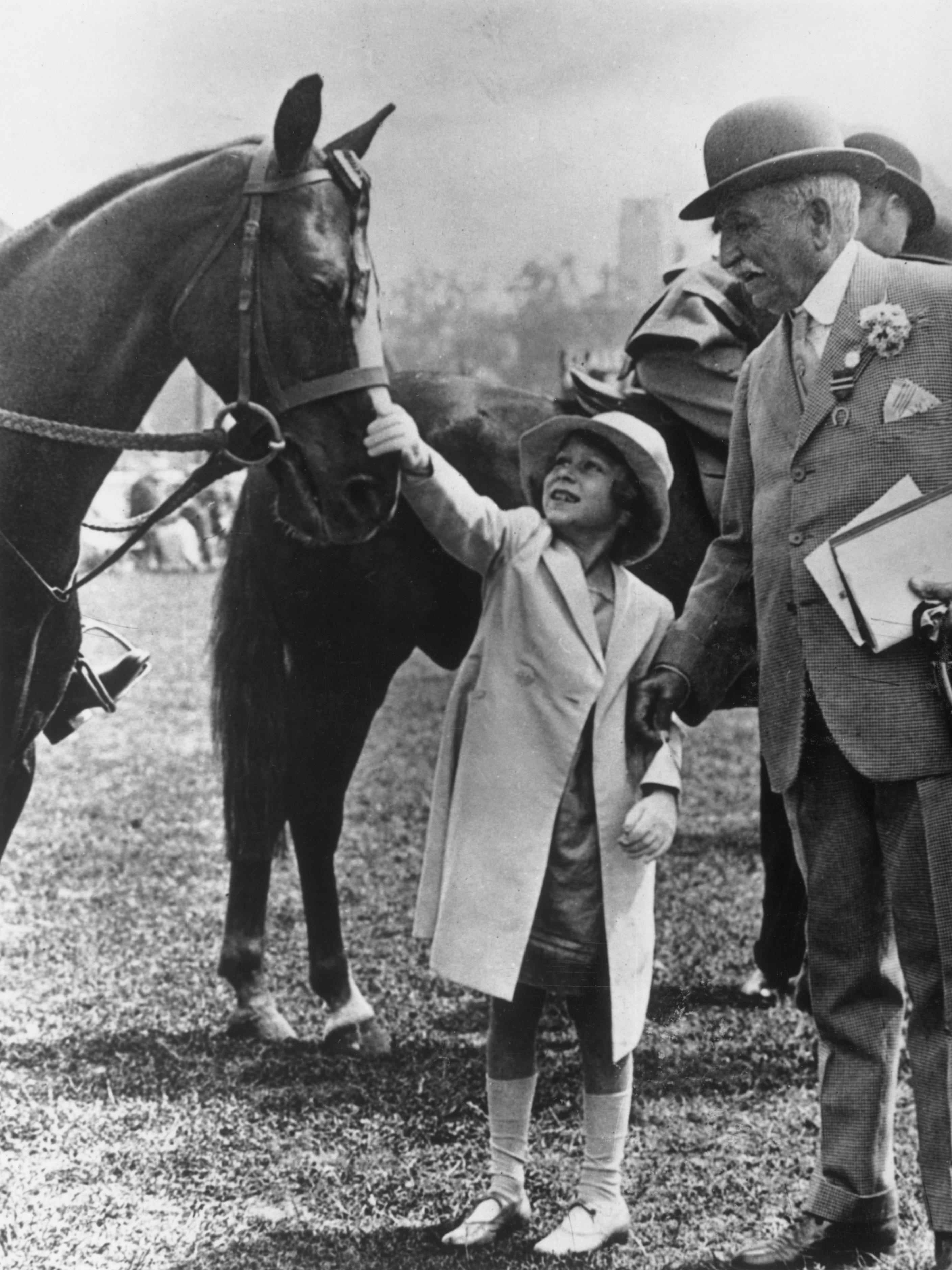 Prinzessin Elizabeth, die spätere Königin Elizabeth II., streichelt am 6. Juni 1934 bei der Richmond Royal Horse Show den Kopf eines Pferdes.