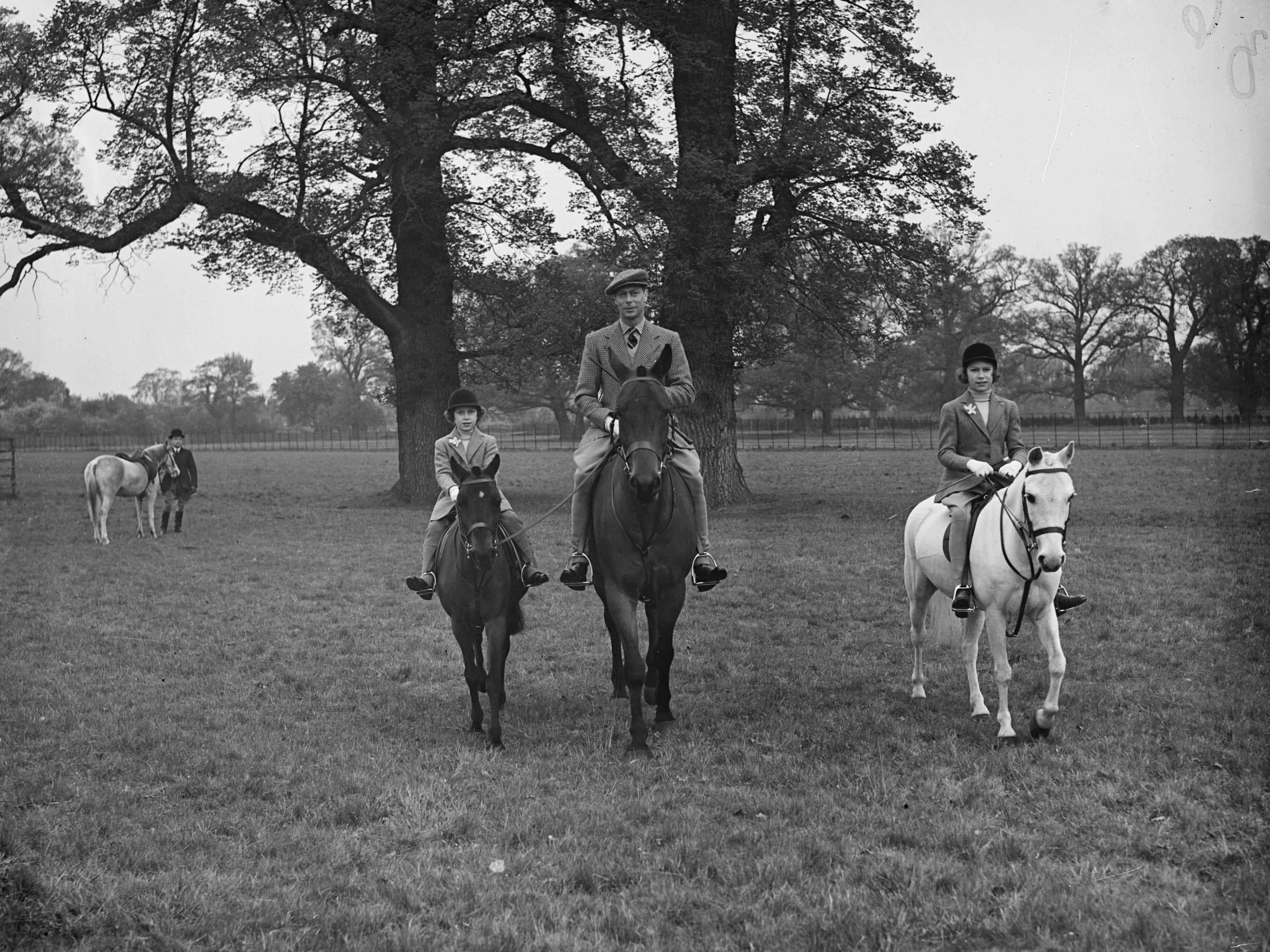 König George VI reitet mit seinen beiden Töchtern auf einem Pferd.