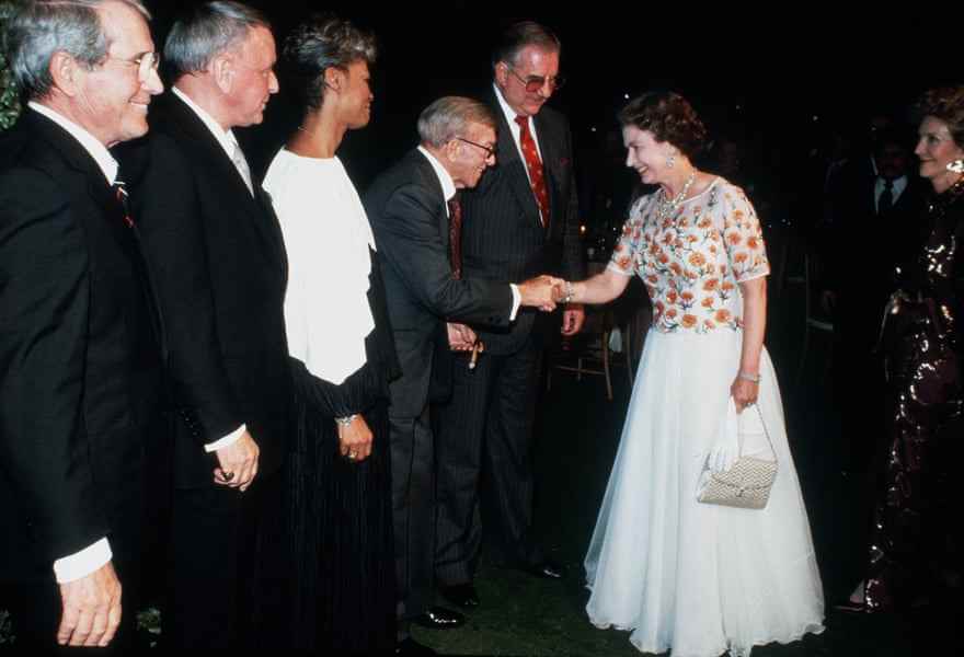 Queen Elizabeth schüttelt George Burns die Hand, beobachtet von (von links) Perry Como, Frank Sinatra und Dionne Warwick bei einem Konzert in Hollywood.
