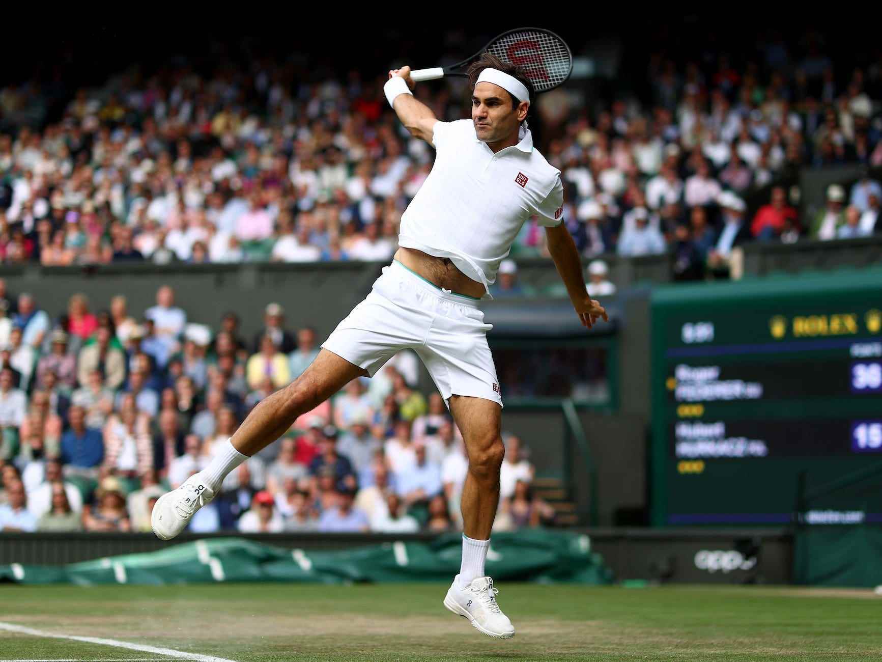 Roger Federer schwebt in der Luft, während er in Wimbledon eine Rückhand schlägt.