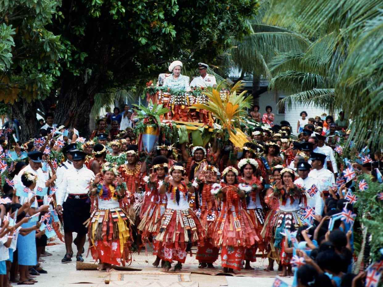 Königin Elizabeth II. und Prinz Philip werden am 27. Oktober 1982 während einer Rundreise durch den Südpazifik in Kriegskanus die Hauptstraße von Tuvalu entlang getragen.
