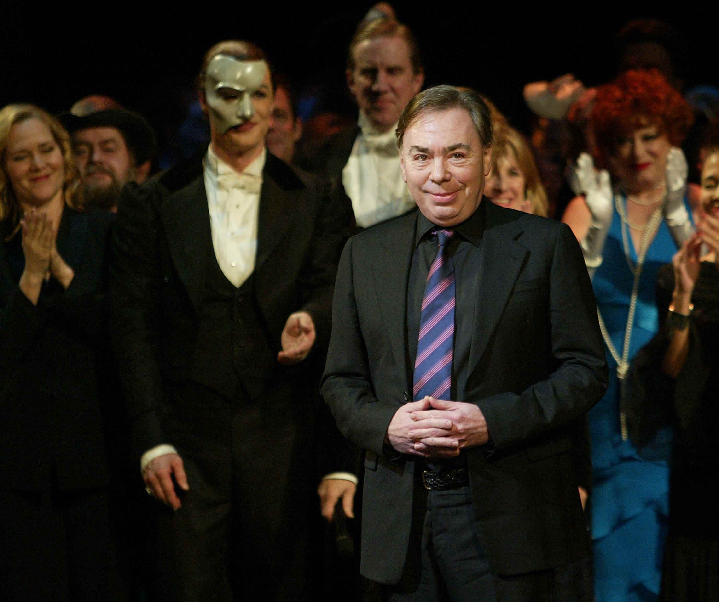 Andrew Lloyd Webber faltet seine Hände in einem schwarzen Anzug und einer gestreiften Krawatte
