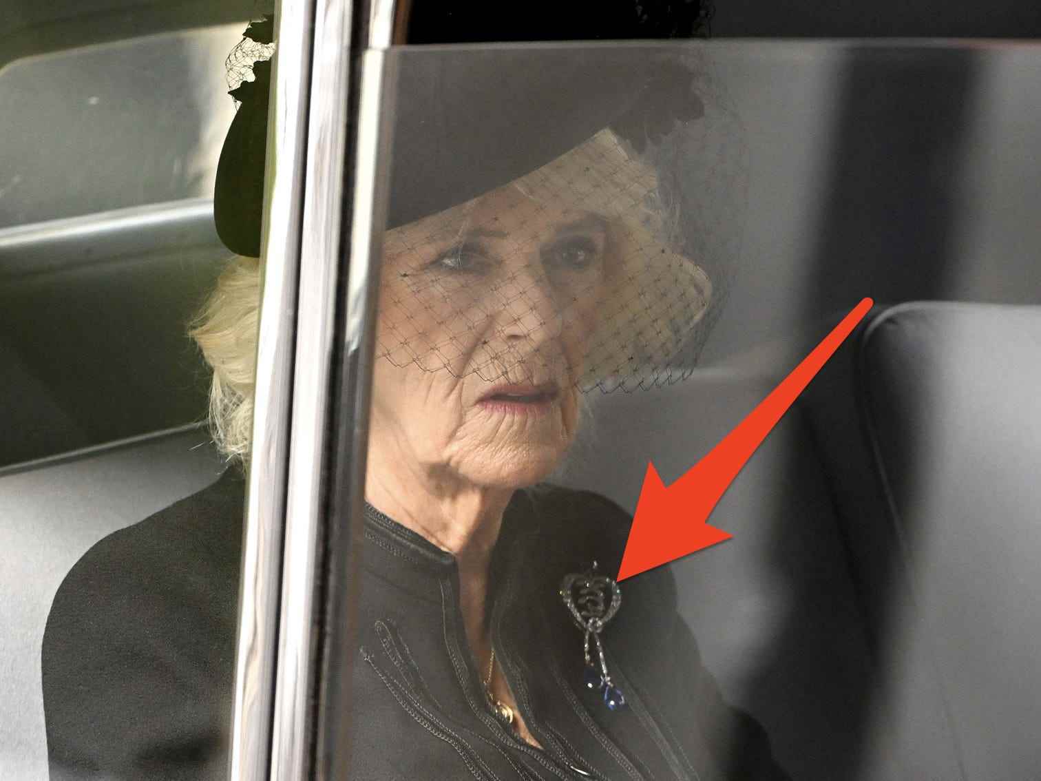 Camilla fährt in einem Auto zur Beerdigung der Königin mit einem Pfeil, der auf ihre Brosche zeigt