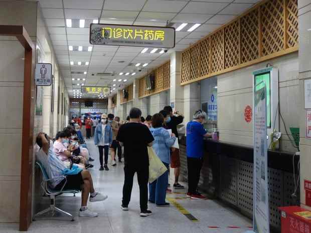 Krankenhauskorridor mit sitzenden und stehenden Menschen, die auf medizinische Hilfe warten