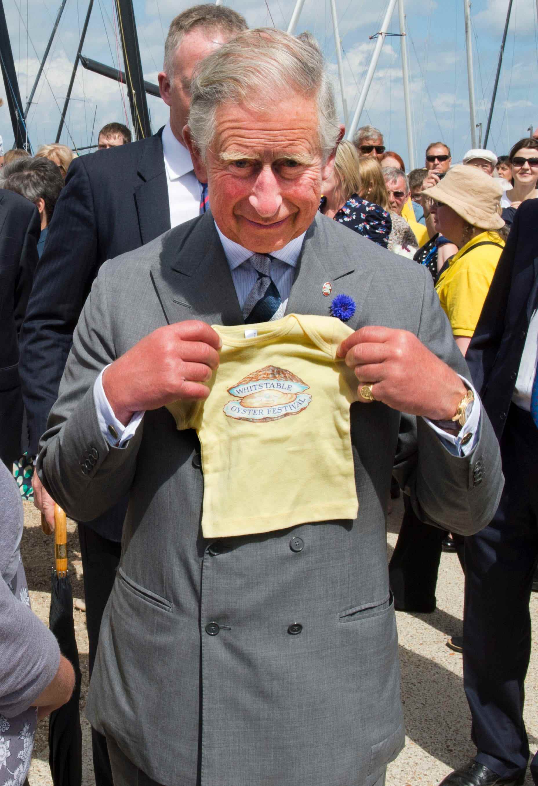 King Charles hält ein Baby-Shirt für Prinz George
