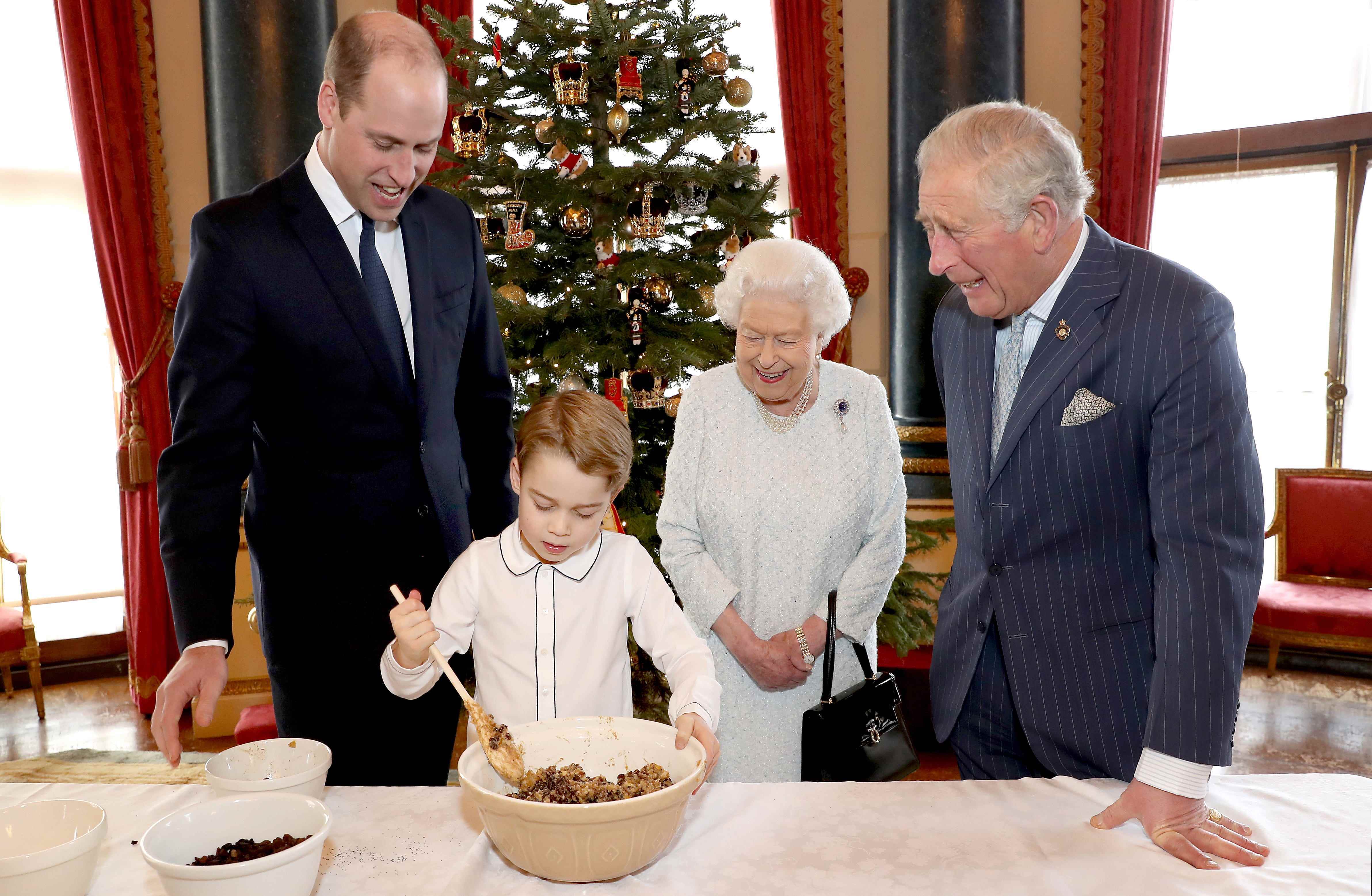 Prinz George mixt einen Weihnachtspudding, während Prinz William, Prinz Charles und Queen Elizabeth zusehen
