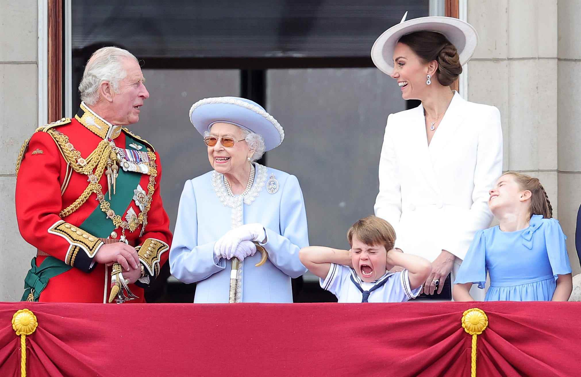 Prinz George hält sich die Ohren zu und schreit, während sich König Charles, Königin Elizabeth und Kate Middleton unterhalten.