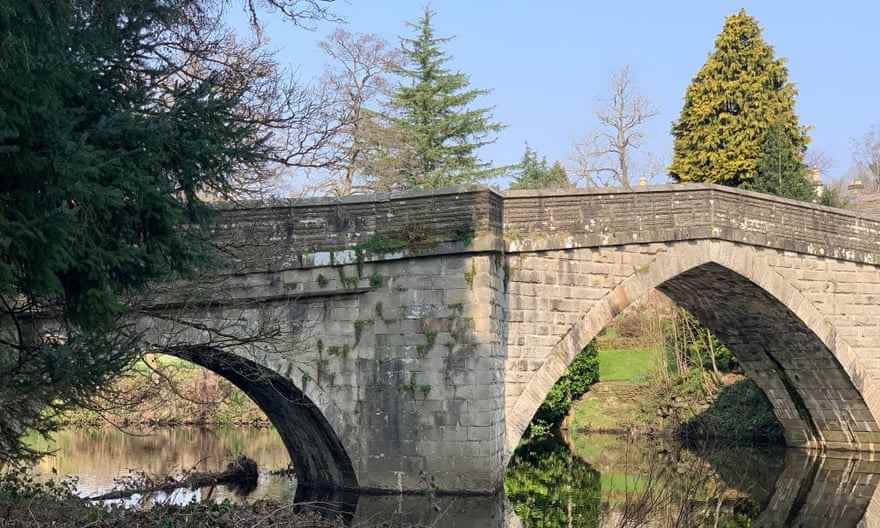 Brick Frogatt Bridge, mit zwei Bögen und Bäumen in der Nähe, über den sehr ruhigen Fluss Derwent