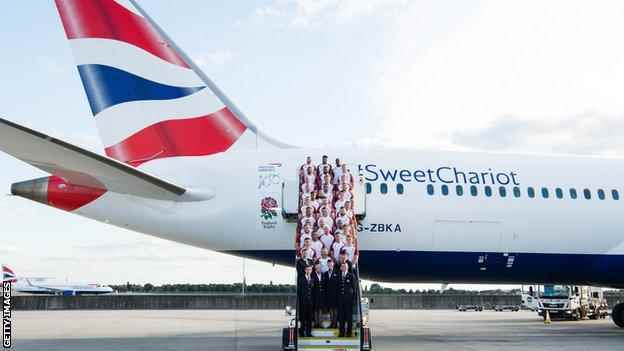 Englands Männer stehen auf den Stufen eines Flugzeugs von British Airways mit dem England Rugby-Logo und den Worten #SweetChariot