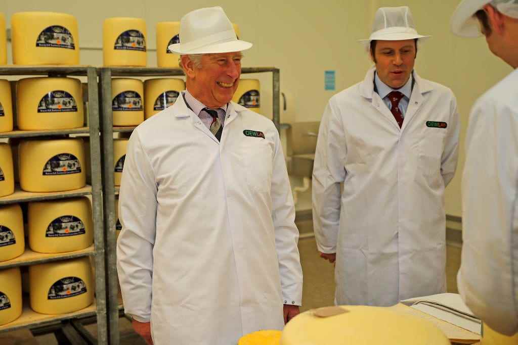 König Charles besucht eine Käserei in einem weißen Mantel und Hut