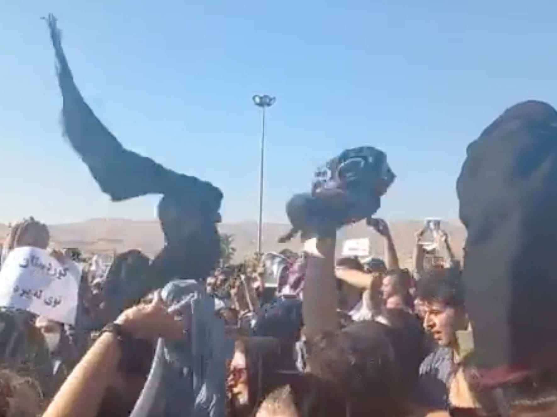 Der Screenshot eines Videos zeigt eine Frau, die mit Kopftüchern in der Luft wedelt