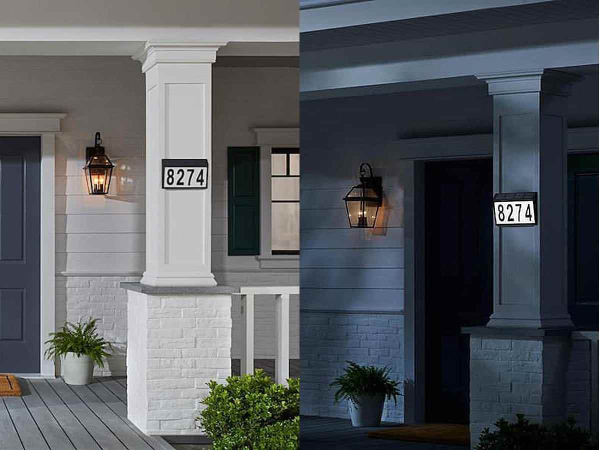 Die schwarzen Nummern 8274 auf einer Tafel mit schwarzem Rand sind bei Tageslicht auf der Säule eines weißen Hauses neben dem gleichen Bild zu sehen, das nachts bei schwachem Licht mit dem weißen Teil des Zeichens beleuchtet ist.