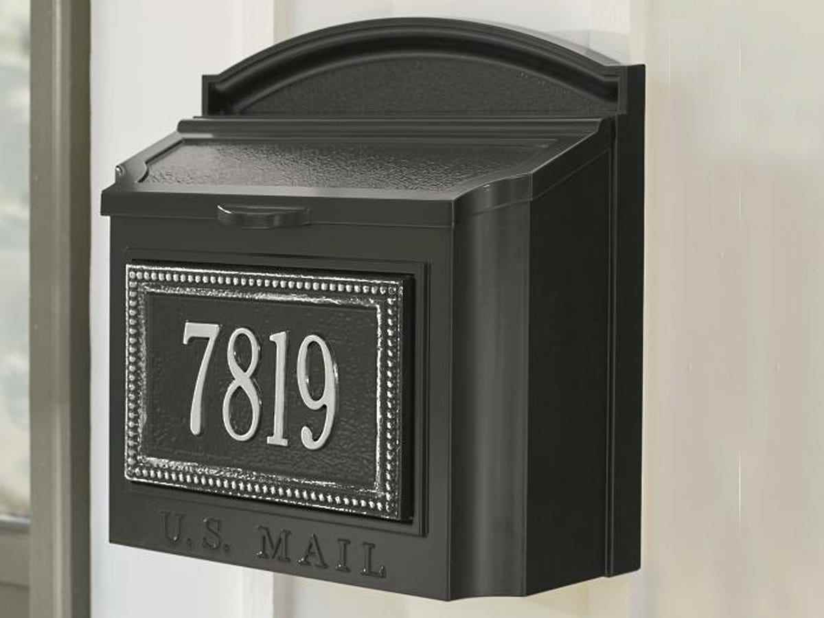 Ein schwarzer klassischer Briefkasten mit oberer Tür hat die Zahlen 7819 in silbernem Text und umgeben von einem silbernen Rand.