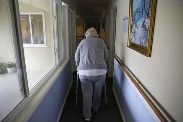Eine ältere Frau geht einen Flur entlang.