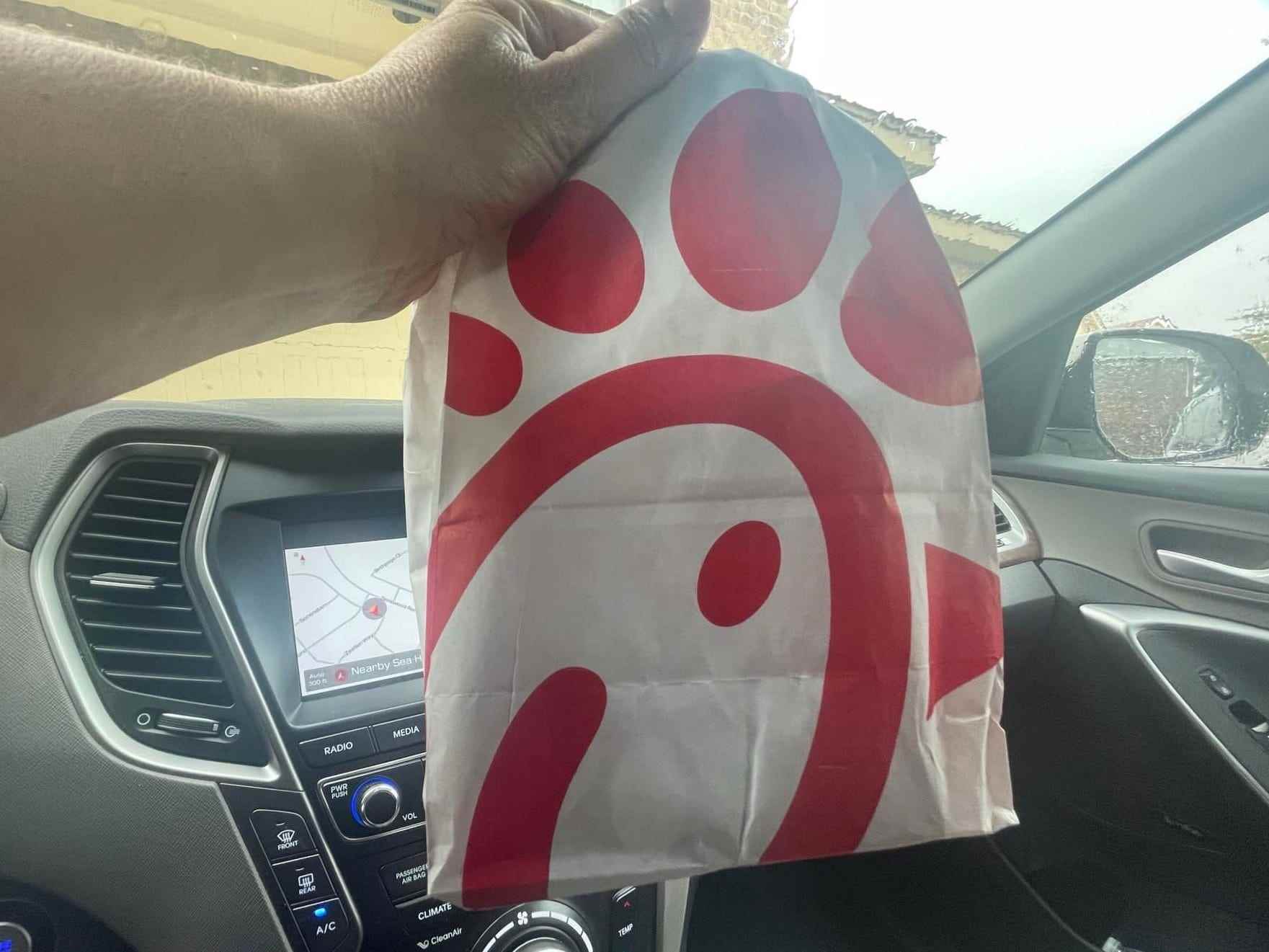 Der Schriftsteller hält eine Tasche mit Chick-fil-A-Logo darauf in einem Auto