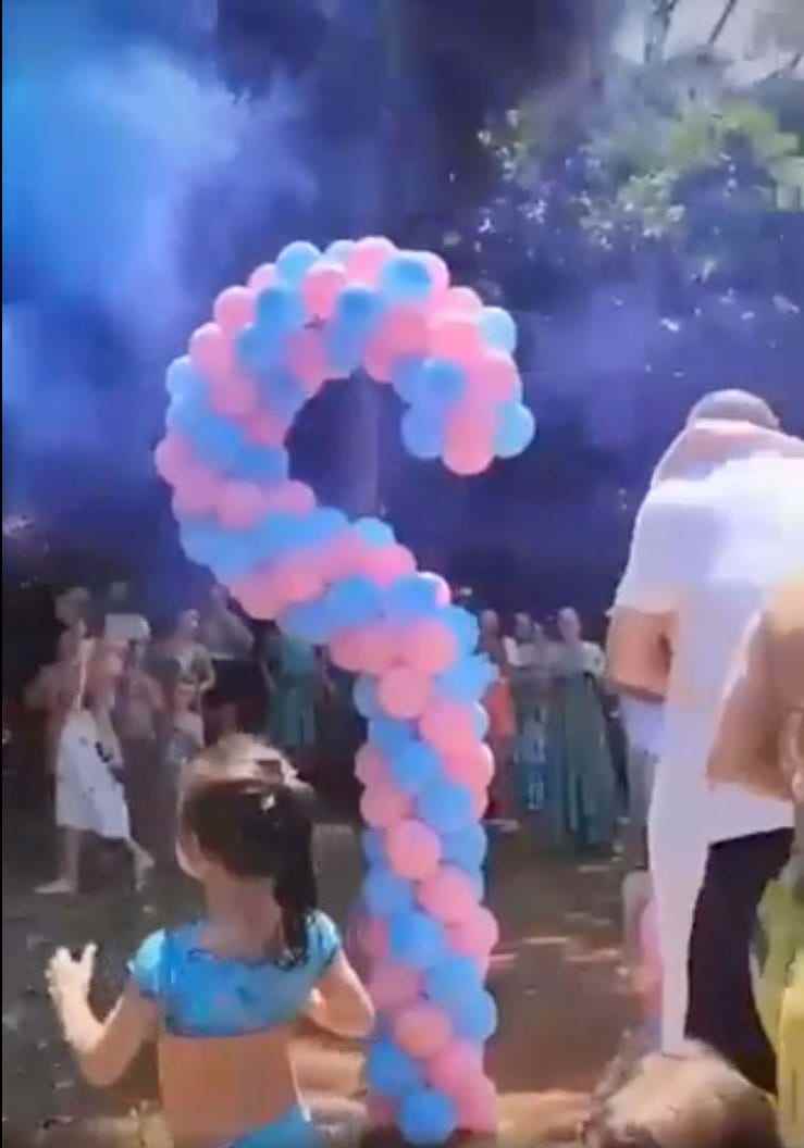 Screenshot eines auf Reddit hochgeladenen Videos, das zwei sich umarmende Personen neben einem Fragezeichen aus blauen und rosa Luftballons zeigt
