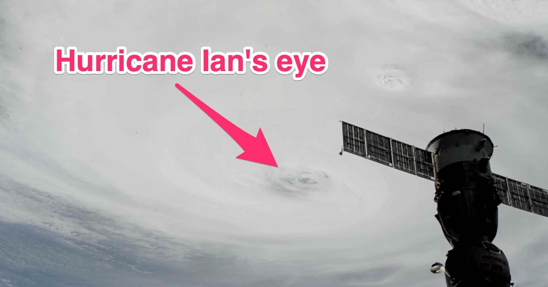 Flügel der internationalen Raumstation, der über einen massiven, wirbelnden Wolkenhurrikan fliegt, wobei der Pfeil auf das Auge zeigt