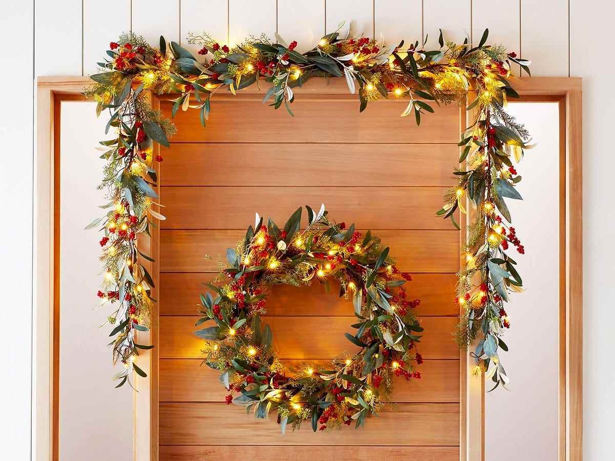 Über einer holzgetäfelten Tür leuchteten ein Kranz und eine Girlande aus Eukalyptus und künstlichen Beeren mit gelben Weihnachtslichtern