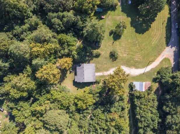 Overhead-Aufnahme eines Hauses auf einem Grundstück, umgeben von Bäumen und mit einer gewundenen Auffahrt